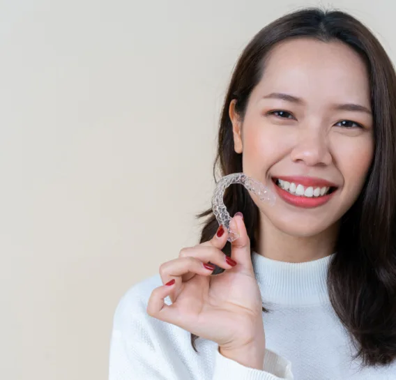 Woman smiling holding clear aligners
